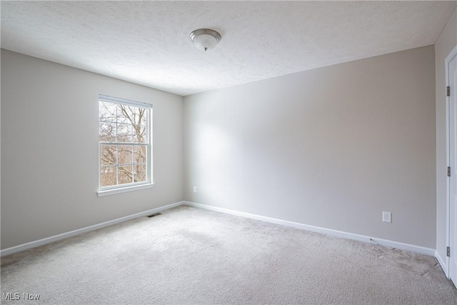 empty room with baseboards, a textured ceiling, visible vents, and light colored carpet