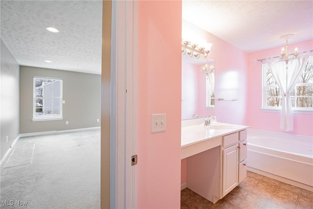 full bathroom featuring a garden tub, a chandelier, a textured ceiling, and vanity