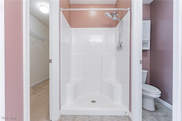 full bath featuring a stall shower, toilet, and baseboards