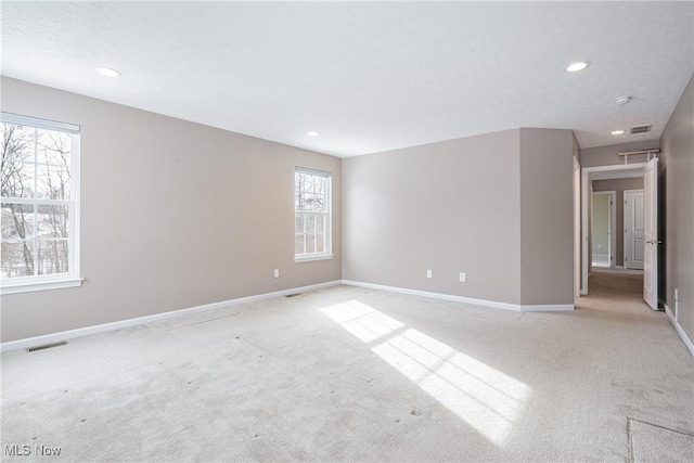 empty room featuring recessed lighting, visible vents, light carpet, a textured ceiling, and baseboards