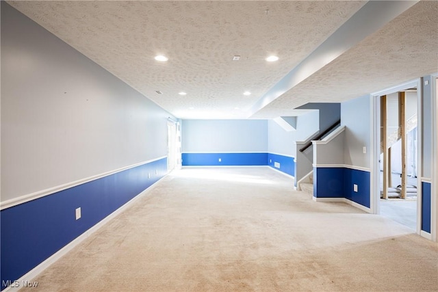 below grade area featuring recessed lighting, light colored carpet, a textured ceiling, baseboards, and stairs