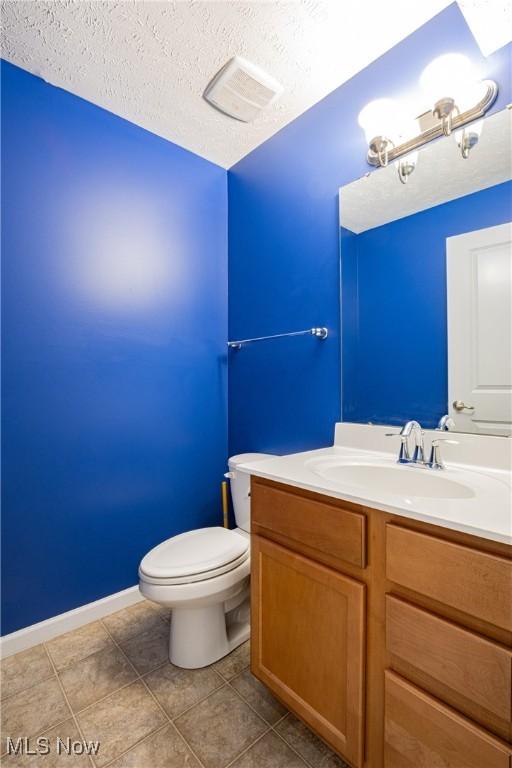 bathroom featuring visible vents, toilet, a textured ceiling, vanity, and tile patterned floors