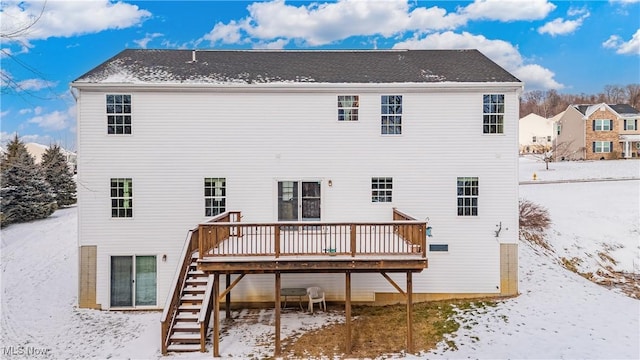 snow covered rear of property with a deck and stairs