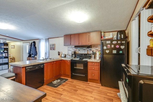 kitchen with a peninsula, a sink, light countertops, black appliances, and light wood finished floors