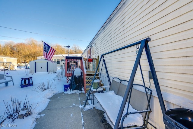 snow covered property with an outdoor structure and a shed