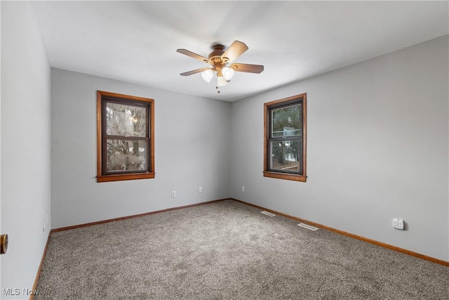 empty room featuring visible vents, carpet, a ceiling fan, and baseboards