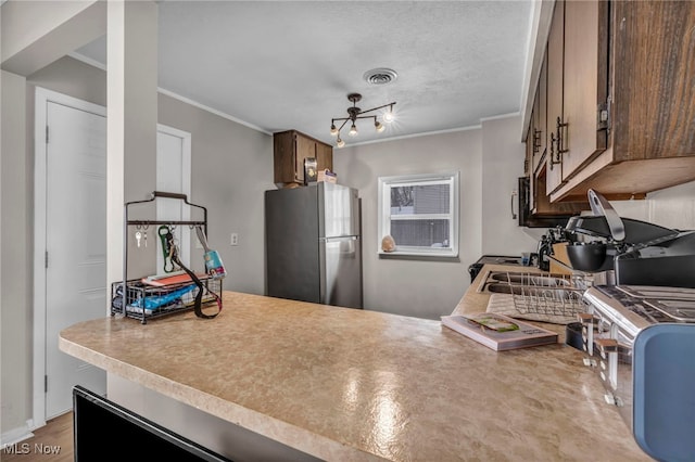 kitchen featuring a textured ceiling, visible vents, light countertops, ornamental molding, and appliances with stainless steel finishes