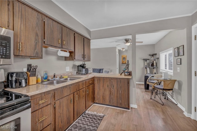 kitchen featuring ceiling fan, light wood-style flooring, appliances with stainless steel finishes, light countertops, and a sink