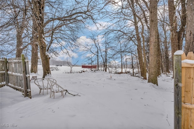 yard covered in snow featuring fence