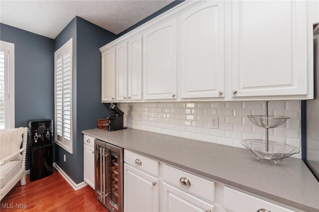 kitchen with light countertops, wine cooler, dark wood-style flooring, and white cabinets