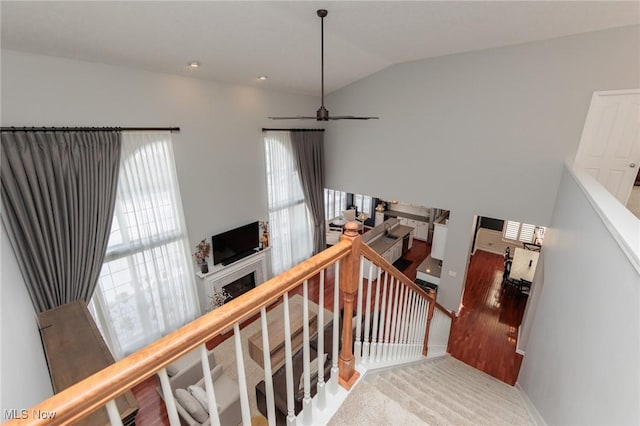 stairs featuring a ceiling fan, lofted ceiling, a fireplace, and baseboards