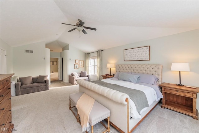 bedroom featuring ceiling fan, ensuite bathroom, light carpet, visible vents, and vaulted ceiling