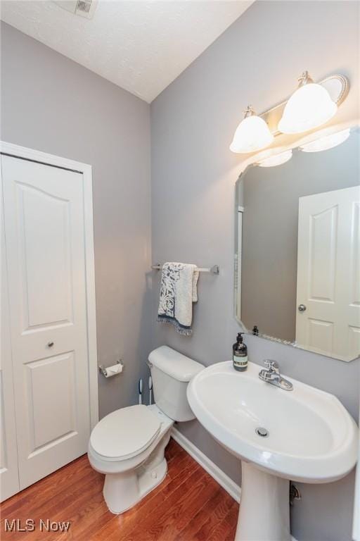 half bathroom featuring toilet, baseboards, and wood finished floors