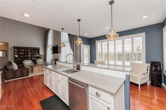 kitchen with decorative light fixtures, light countertops, stainless steel dishwasher, open floor plan, and white cabinetry