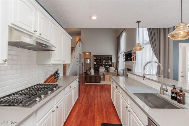 kitchen with pendant lighting, light countertops, and under cabinet range hood