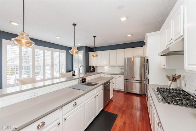 kitchen featuring decorative light fixtures, light countertops, appliances with stainless steel finishes, white cabinetry, and a sink