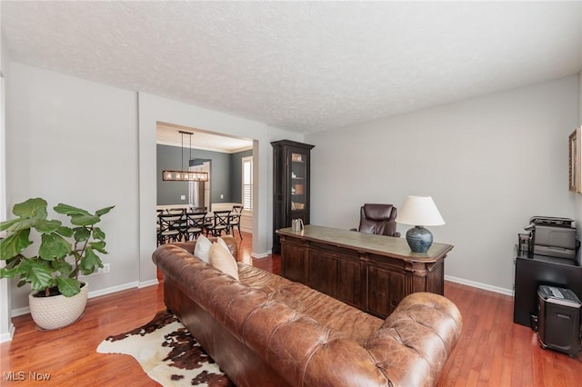 office space with a textured ceiling, baseboards, and wood finished floors