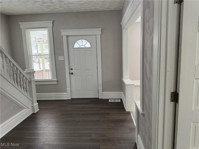 entryway featuring stairway, dark wood-style flooring, visible vents, and baseboards