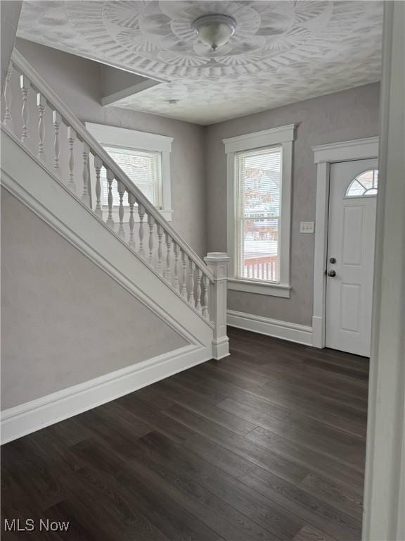 entryway featuring dark wood-type flooring, stairway, and baseboards