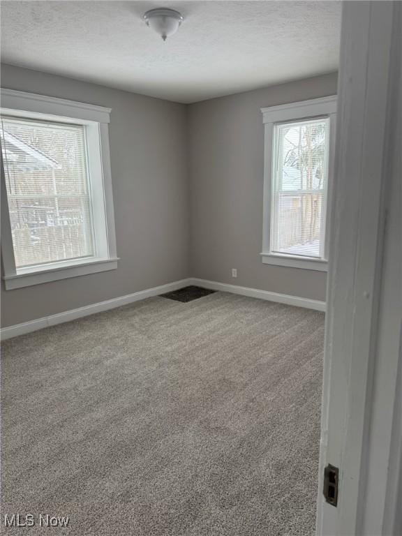 carpeted empty room with a textured ceiling and baseboards