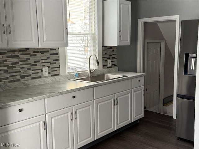 kitchen featuring stainless steel fridge, white cabinets, a sink, and light countertops