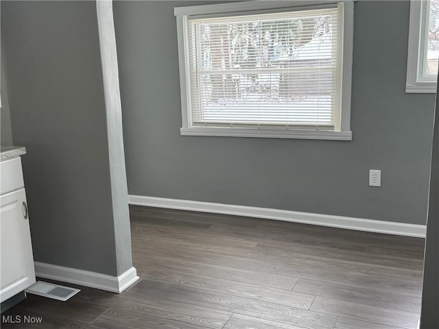 interior space with dark wood-style flooring, visible vents, and baseboards