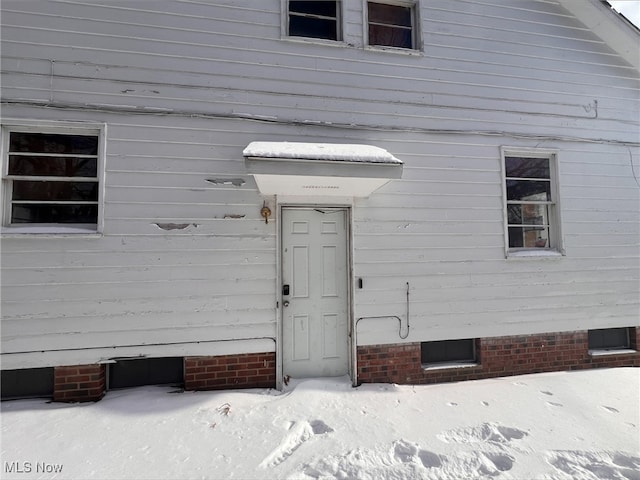 snow covered property entrance with crawl space