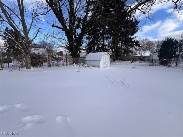 yard covered in snow with an outbuilding, fence, and a storage shed