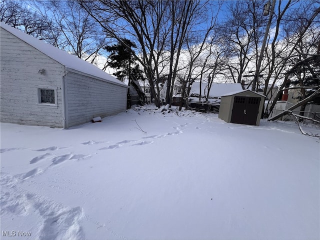 yard covered in snow featuring an outdoor structure, a detached garage, and a shed