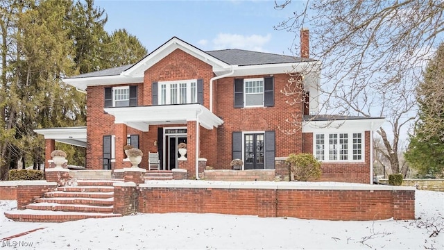 view of front of home featuring french doors, brick siding, and a chimney