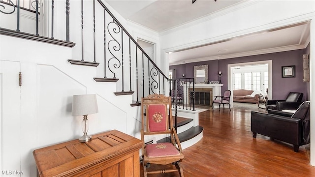 entrance foyer featuring stairs, a fireplace, ornamental molding, and wood finished floors