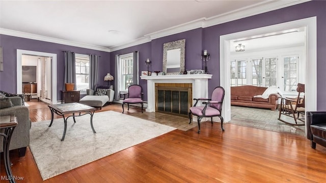 living area featuring a fireplace with flush hearth, ornamental molding, and wood finished floors