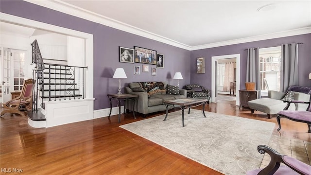 living area featuring baseboards, crown molding, stairway, and wood finished floors