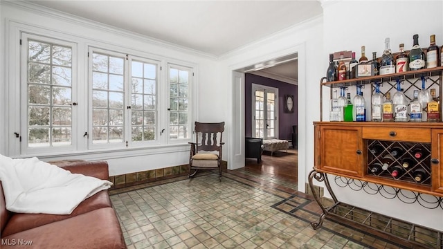 living area with baseboards, crown molding, and a dry bar