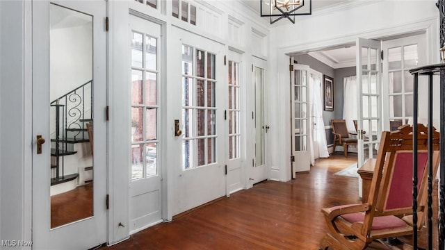 doorway to outside featuring a healthy amount of sunlight, dark wood-style flooring, a baseboard radiator, and crown molding