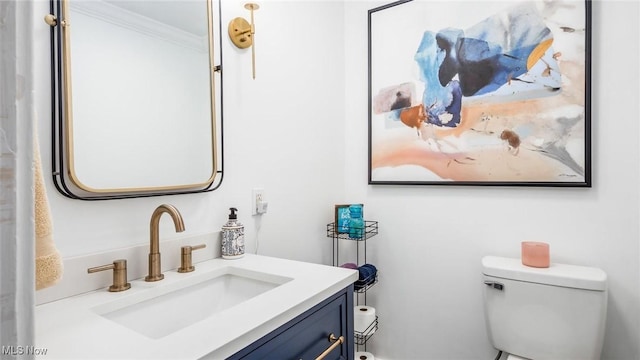 bathroom with ornamental molding, vanity, and toilet