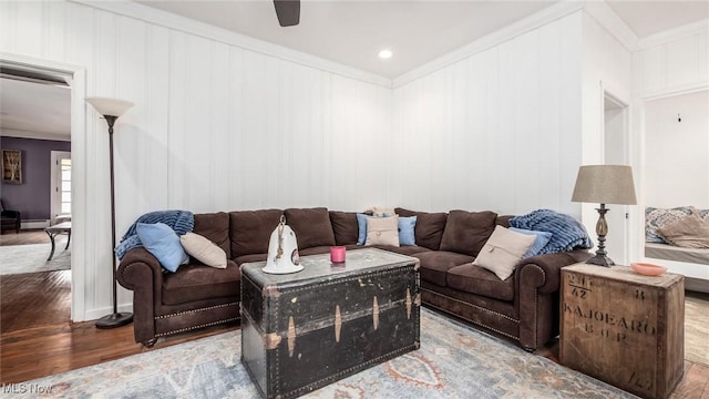 living area with a baseboard heating unit, ornamental molding, wood finished floors, and baseboards