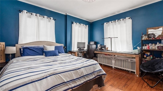 bedroom with radiator, crown molding, and wood finished floors