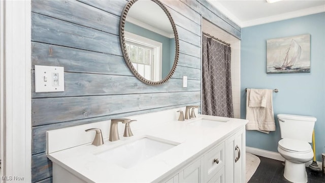 bathroom featuring double vanity, a sink, toilet, and baseboards