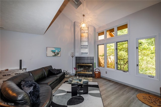 living area with high vaulted ceiling, a fireplace, wood finished floors, and baseboards