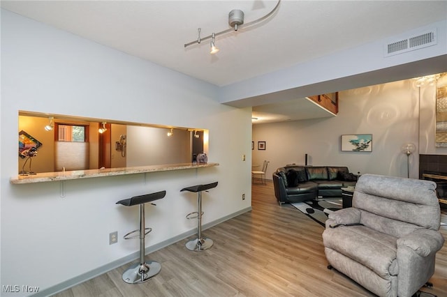 living room with visible vents, light wood-style flooring, and baseboards