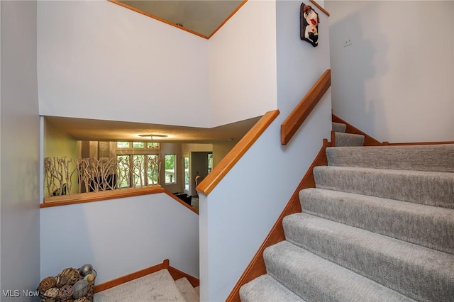 stairs with carpet floors, a towering ceiling, and baseboards