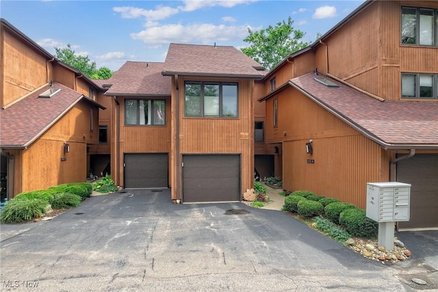 view of front of house featuring a garage, roof with shingles, and driveway