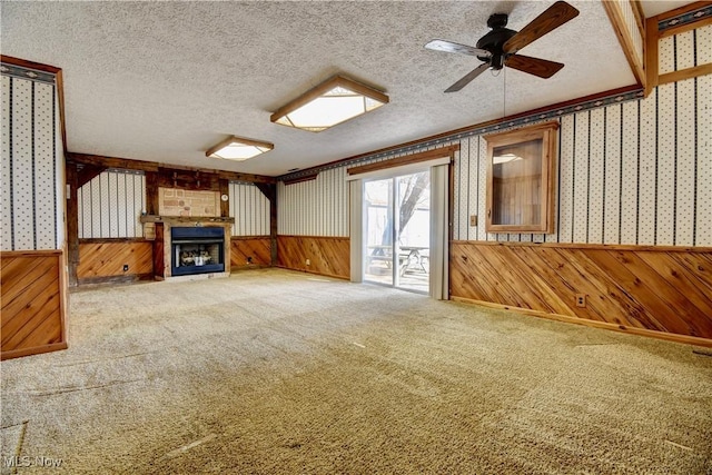 unfurnished living room with a wainscoted wall, a textured ceiling, and wallpapered walls