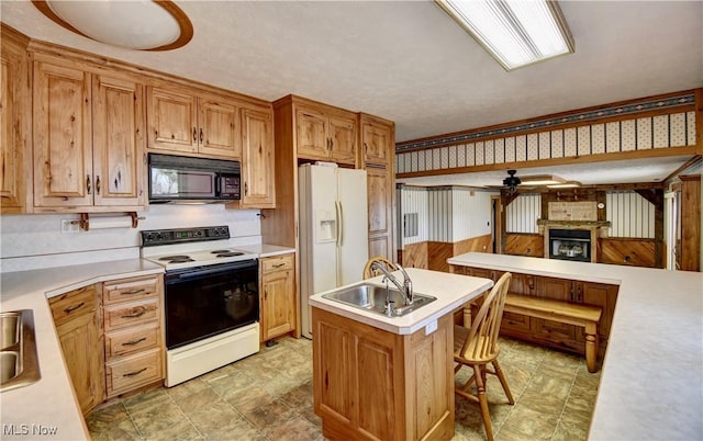 kitchen with white appliances, a kitchen island, a sink, light countertops, and wallpapered walls