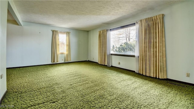 spare room featuring carpet, a textured ceiling, plenty of natural light, and baseboards