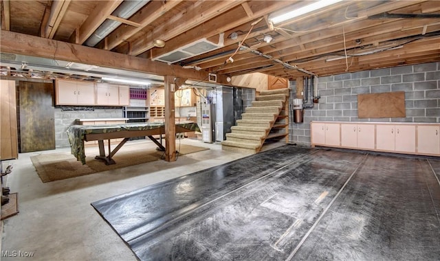 unfinished basement with pool table, heating unit, and stairs