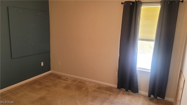 unfurnished room with light carpet and baseboards