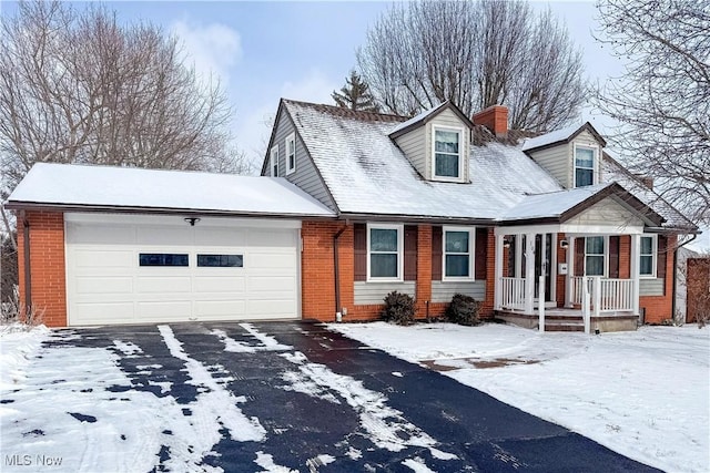 cape cod-style house featuring brick siding, a chimney, an attached garage, and aphalt driveway