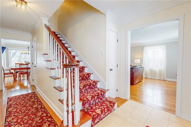 stairs with baseboards, wood finished floors, and crown molding